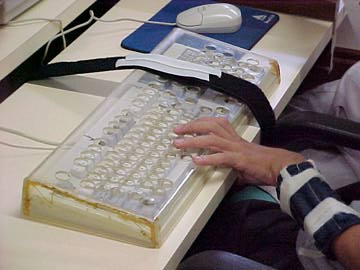 Foto de aluno digitando utilizando pulseira de pesos no bra�o