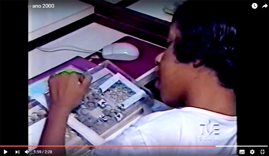 Imagem de um vdeo no qual aparece uma jovem utilizando um computador com o teclado adaptado com recursos de Tecnologia Assistiva